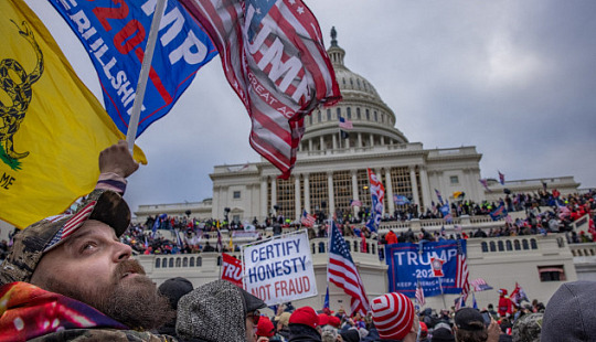 A crowd of protesters gathered outside the U.S. Capitol building, waving flags and holding signs supporting Donald Trump, during a political rally.